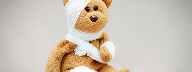 Teddy bear with bandage on gray background.